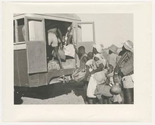 "1950 '400 Series' / 87 B/W prints (some duplicates) / Ovamboland": Man loading items on a truck, and a group of people standing next to it (print is a cropped image)