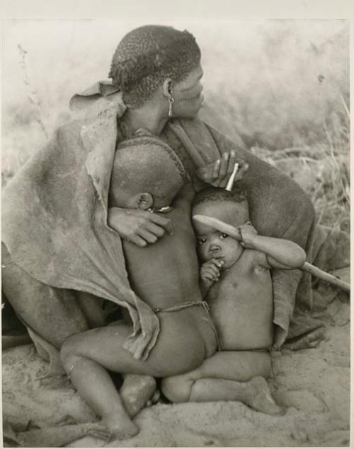 [No folder title]: Woman from "visiting group" sitting with two children leaning against her








