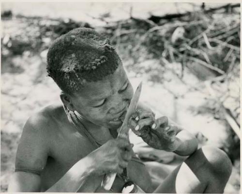 [No folder title]: Tsekue eating meat, cutting a bite off at her lips with a knife








