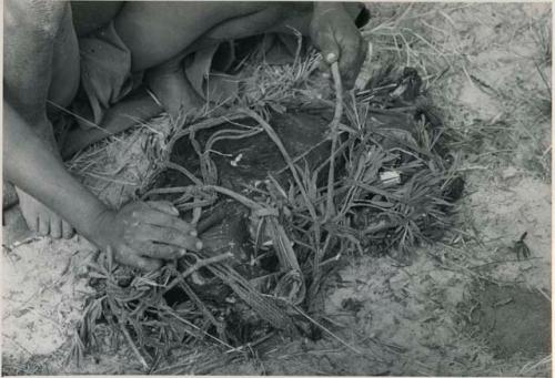 [No folder title]: Close-up of !Gai's hands tying up a carrying net









