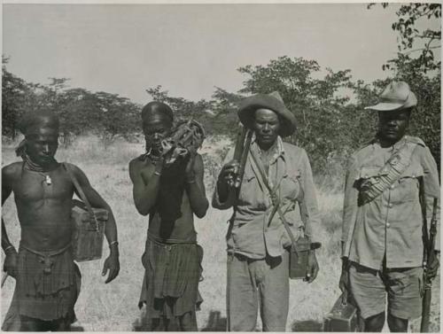 "1950 '400 Series' / 41 prints": Four men standing and holding guns and cases (print is a cropped image)