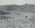 "1950 400 series  43 prints / Kunene River, Kaokoveld, Ovamboland / Merle LaVoy & L.K.M": Five men climbing a hill (print is a cropped image)