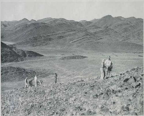 "1950 400 series  43 prints / Kunene River, Kaokoveld, Ovamboland / Merle LaVoy & L.K.M": Five men climbing a hill (print is a cropped image)