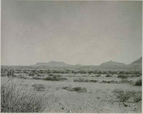 "1950 400 series  43 prints / Kunene River, Kaokoveld, Ovamboland / Merle LaVoy & L.K.M": Small pile of rocks at right, with hills in the distance (print is a cropped image)