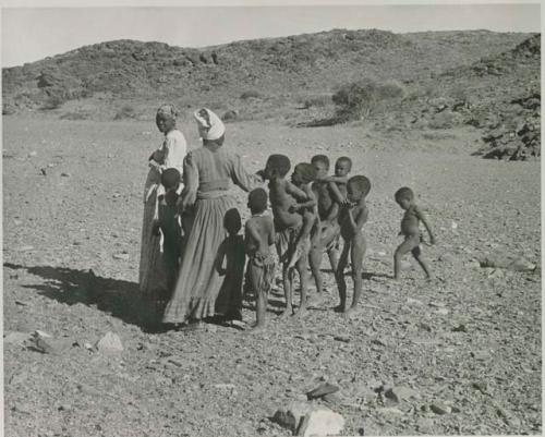 "1950 400 series  43 prints / Kunene River, Kaokoveld, Ovamboland / Merle LaVoy & L.K.M": Group of women and children walking (print is a cropped image)