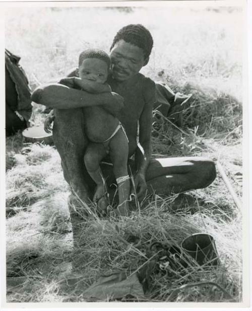 [No folder title]: "Gao Medicine" sitting and holding Debe against his knee (print is a cropped image)