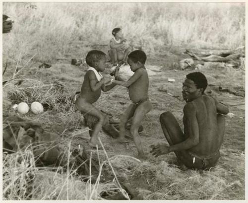 [No folder title]: "Gao Medicine", seated, "Little ≠Gao", /Gaishay (Di!ai's and "Gao Medicine's" son), and other unidentified people in the background (print is a cropped image)