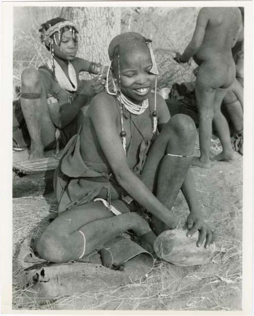 [No folder title]: "Visiting girl" sitting and holding a piece of veldkos (print is a cropped image)