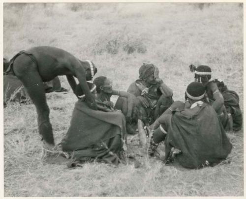 [No folder title]: Medicine man curing another person from a group of seated people (print is a cropped image)