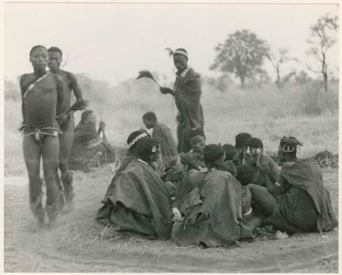 [No folder title]: Men dancing around a gathering of women (print is a cropped image)