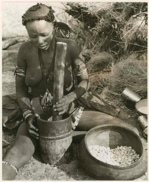 [No folder title]: Close up of Di!ai (wife of Gao) pounding something, using a mortar (print is a cropped image)