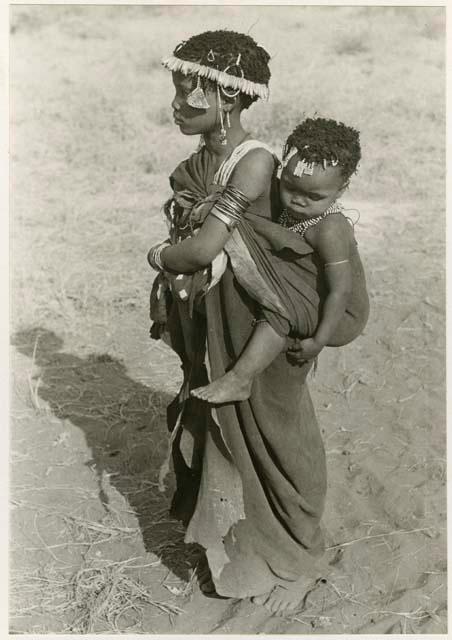 [No folder title]: Girl with a wreath of blossoms around her head, carrying a baby (print is a cropped image)