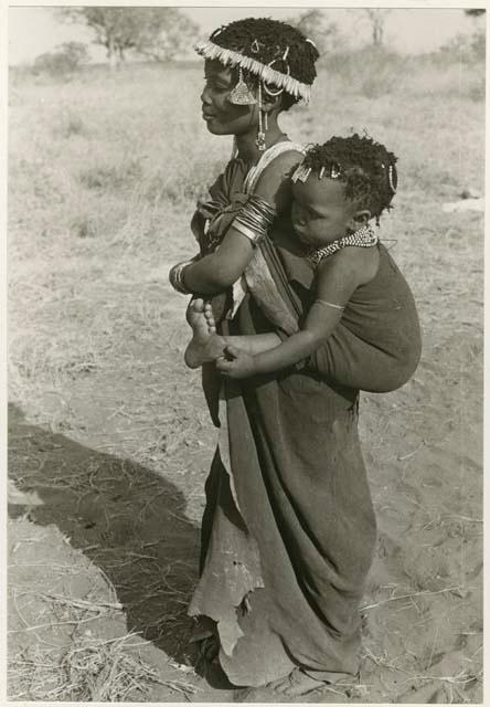 [No folder title]: Girl with a wreath of blossoms around her head, carrying a baby (print is a cropped image)