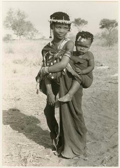 [No folder title]: Girl with a wreath of blossoms around her head, carrying a baby (print is a cropped image)