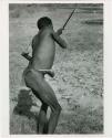 [No folder title]: "Crooked /Qui" demonstrating shooting an arrow, seen from the back (print is a cropped image)