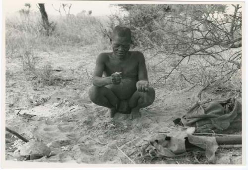 [No folder title]: Oukwane squatting in werft while squeezing juice (print is a cropped image)