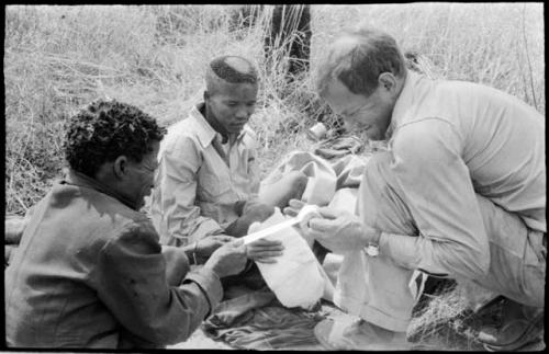 William Donnellan bandaging "/Qui Hunter's" leg with ≠Toma's assistance

