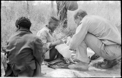 William Donnellan bandaging "/Qui Hunter's" leg with ≠Toma's assistance
