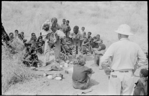 William Donnellan carrying "/Qui Hunter" to the truck with Laurence Marshall, Elizabeth Marshall Thomas, Kernel Ledimo, and other Ju/'hoansi present