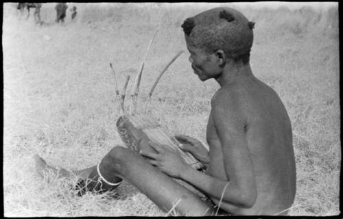 "/Gao Music" sitting with a //guashi, seen from behind