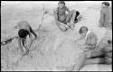 Children likely constructing a playhouse in the sand with sticks, "/Qui Navel" and ≠Toma watching