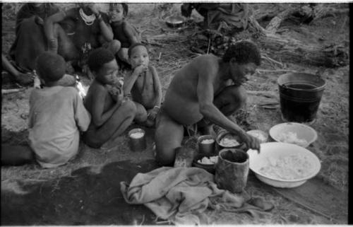 "Old Gau" distributing cooked mealies and a group of children, including !Naishi and "Little ≠Gao" (son of "/Qui Navel" and //Kushay), sitting behind him