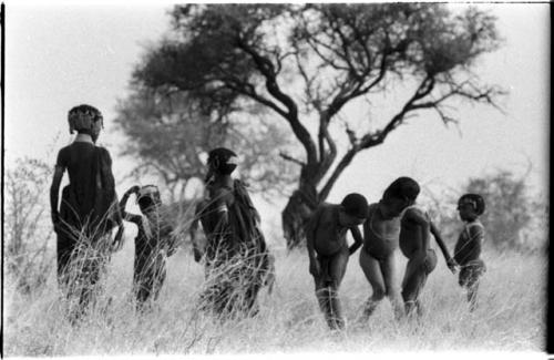 Children standing in grass, including three boys dancing