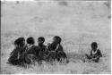 Girls clapping and singing in a circle and a boy sitting apart