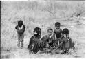 Girls clapping and singing in a circle, with a little boy dancing