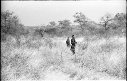 Two women and a child walking in the grass, seen from a distance