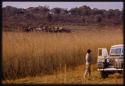 Lorna Marshall looking at a village, standing near Expedition Land Rover