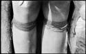 Person's legs with beads worn by Ju/'hoan women below their knee and a thong bracelet