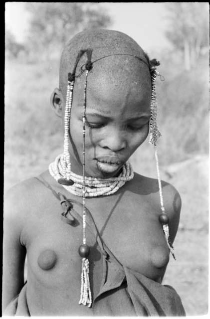 Portrait of a visiting girl with her head shaved, showing ostrich eggshell bead necklace