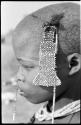 Close-up of bead accessory hanging from tuft of hair of a visiting girl