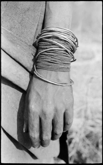 Person's hand showing wire and fiber cord bracelets