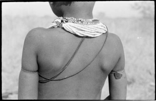 /Gaishay, son of "Gao Medicine," wearing necklace and strands of vegetable fiber cord, seen from the back