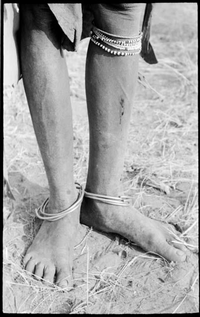 Metal rings on ankles, bead and grass bracelets under knee