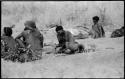 Bau leaning over her mother //Khuga's knee, with two men sitting before them