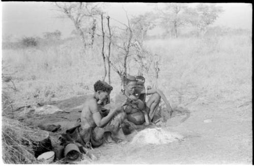 Xuan//a (one of Gau's wives) and her baby, ≠Toma, sitting by their fire