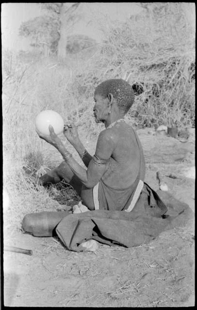 "Old Xama" cleaning out an ostrich eggshell with a stick