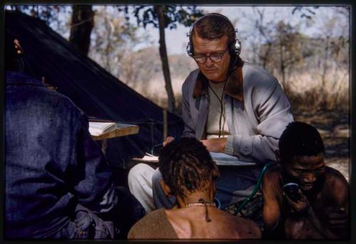 Three people sitting, with Nicholas England taking notes