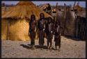 Four girls standing in front of a hut