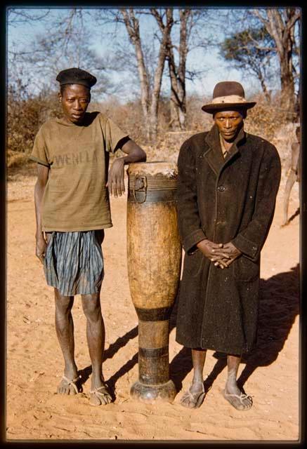 Two men standing next to a drum