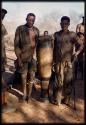 Two men standing next to a drum