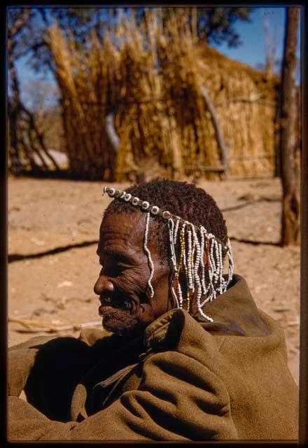 Medicine man wearing a beaded headdress, profile