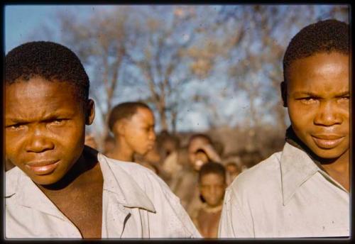 Two boys standing, with other people in the background