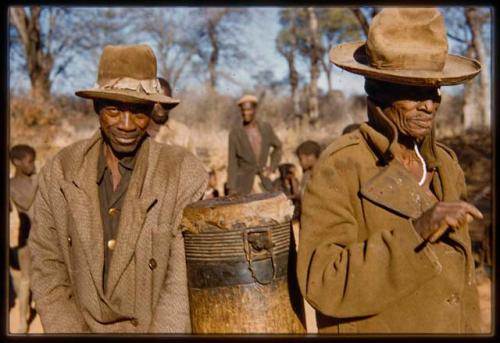 Two men standing next to a drum