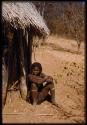 Girl sitting next to a hut
