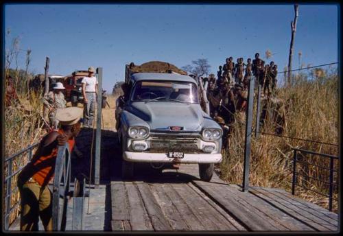 Men standing near an expedition truck boarding the pont (ferry) at Bagani