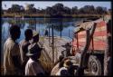 Men standing and watching the expedition Dodge boarding the pont (ferry) at Bagani